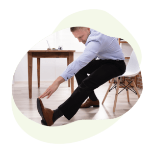 Business man stretching at desk reaching for foot